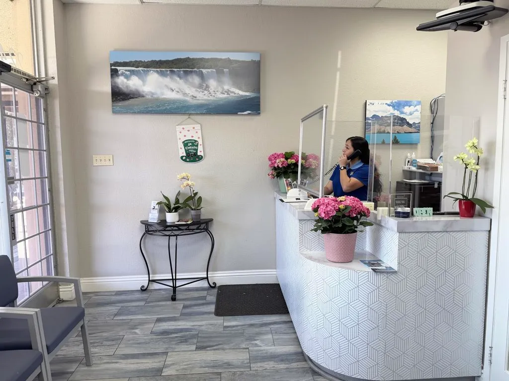Anaheim Implants & Dental Group reception desk with dental assistant and floral arrangements.