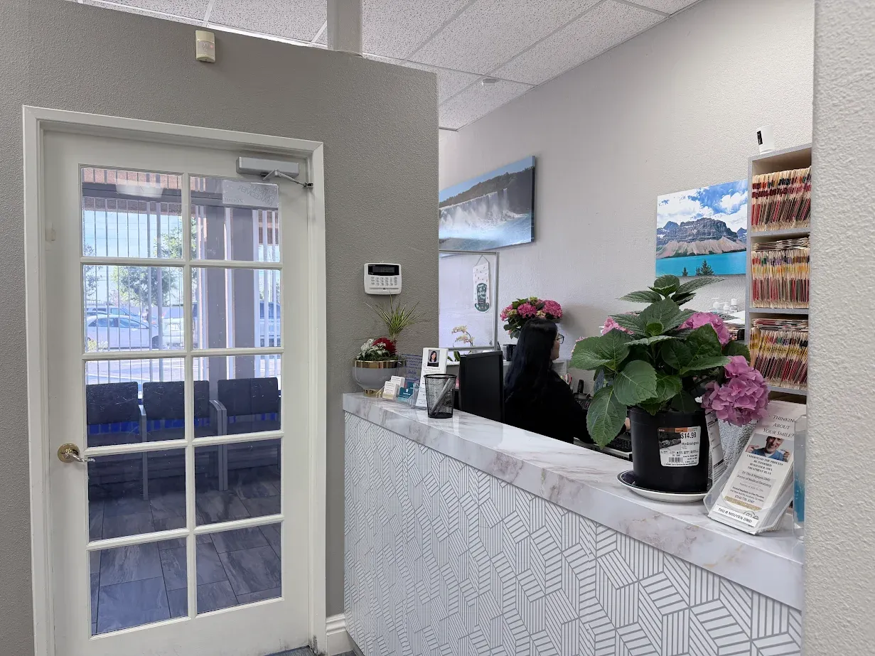 Bright office reception desk with a receptionist, pink flowers, and a glass door